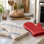 Quilted cotton oven mitts and a silicone oven mitt on a kitchen counter